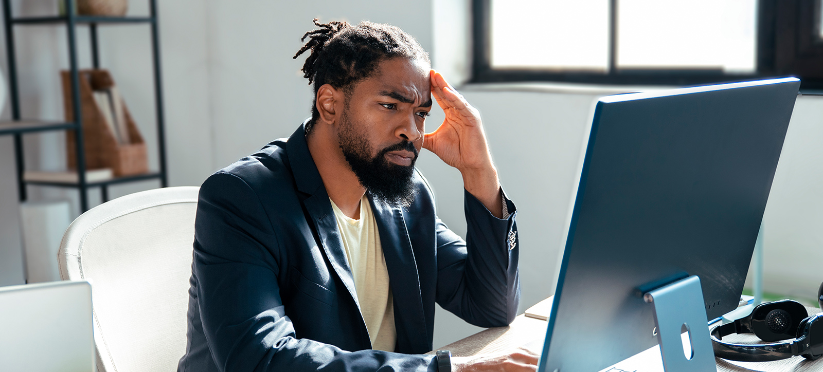 Small Business owner holds his head as he looks at a computer screen
