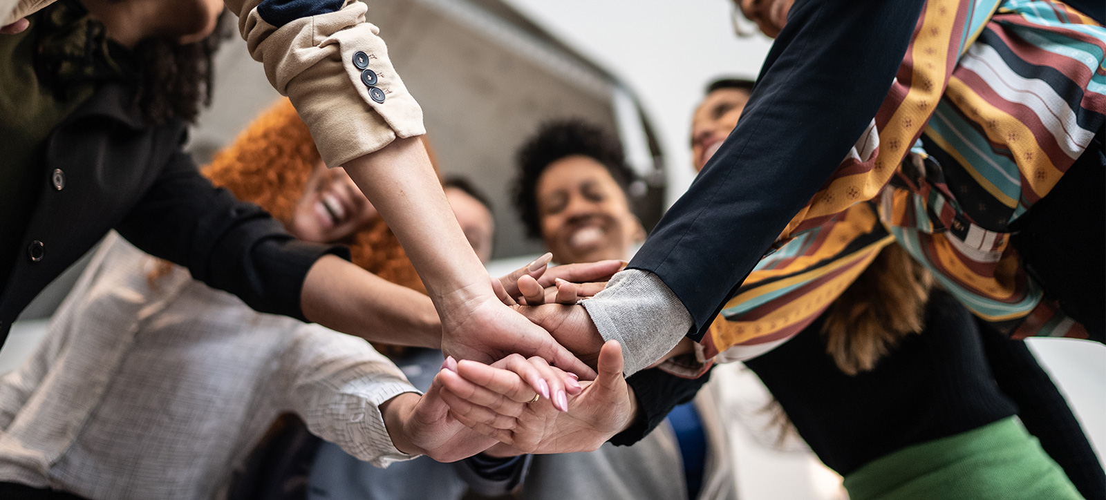 A group of professionals from different backgrounds huddle up like a team to illustrate prosocial co-operation.