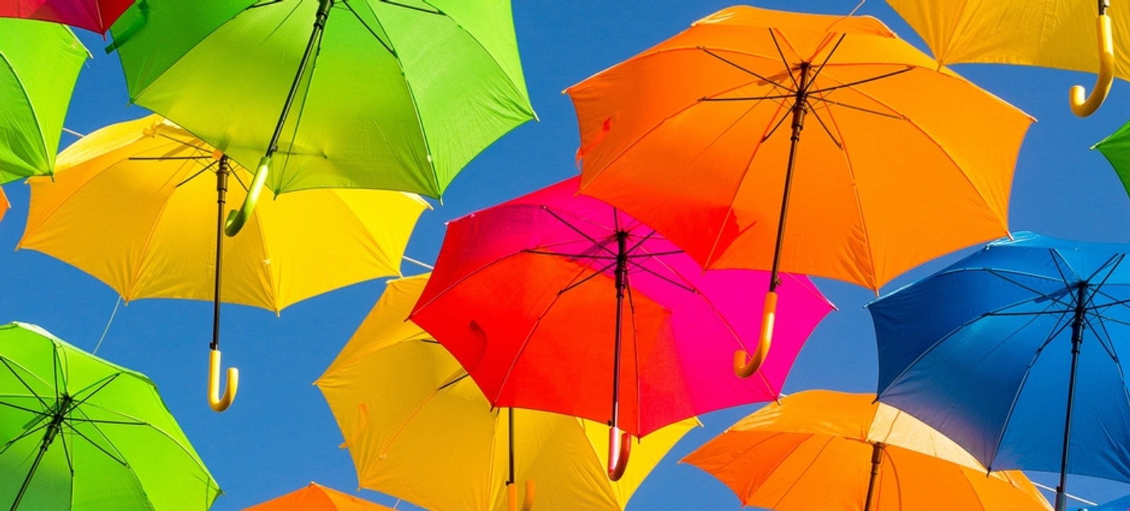 Colourful umbrellas hanging above the ground against a blue sky in the background. Colourful umbrellas hanging above the ground against a blue sky in the background.