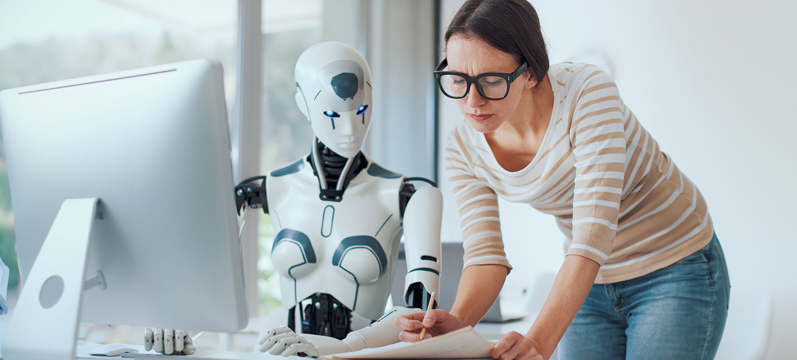 A human employee works with her AI-powered robotic colleague at an office desk, demonstrating the challenges of working with generative AI. A human employee works with her AI-powered robotic colleague at an office desk, demonstrating the challenges of working with generative AI.
