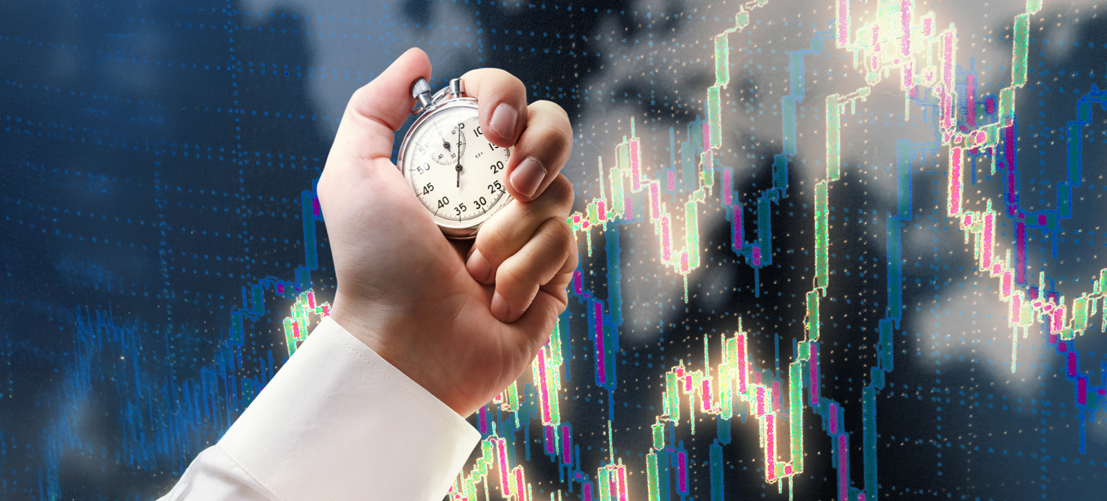 A close-up photograph of a businessperson's hand holding a stop watch. The backdrop are digital graphs tracking financial performance on the markets.