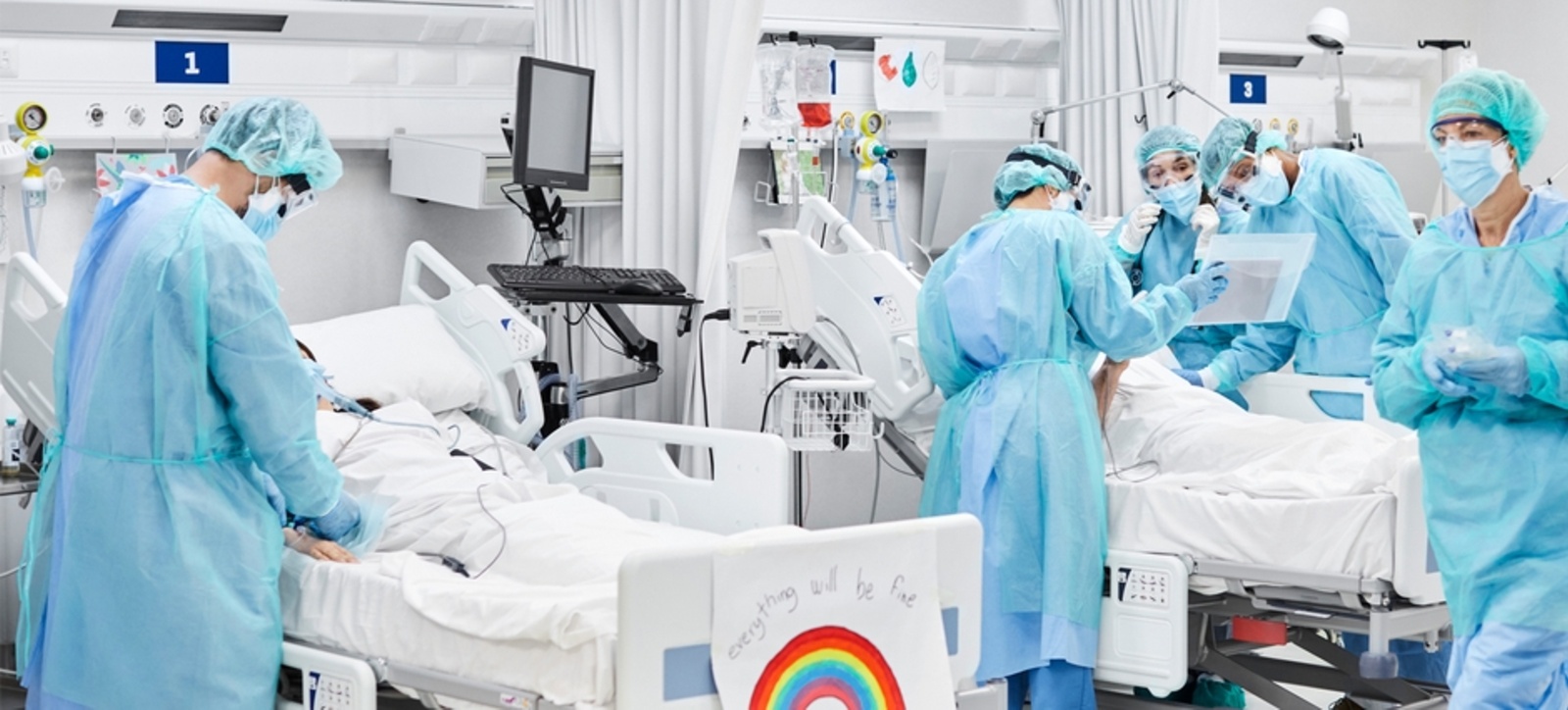 A team of five medical staff working around two patients in bed on a hospital ward. A team of five medical staff working around two patients in bed on a hospital ward.