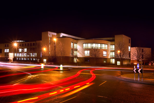 A road and roundabout at night with car headlights under slow exposure